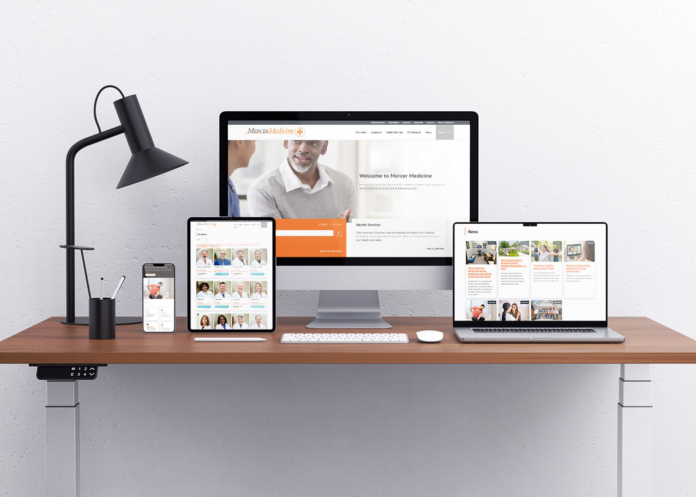 A mobile phone, tablet, desktop monitor and laptop atop a desk showcasing webpages from the Mercer Medicine website