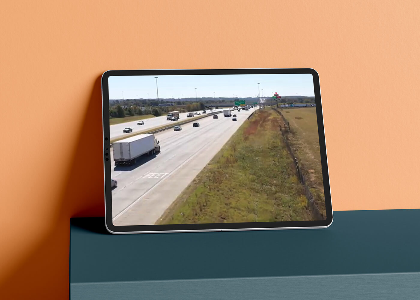 Tablet displaying drone footage of freight trucks on a highway